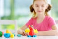 Cute little girl having fun with colorful modeling clay at a daycare. Creative kid molding at home. Royalty Free Stock Photo