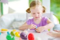 Cute little girl having fun with modeling clay at a daycare. Creative kid molding at home. Royalty Free Stock Photo