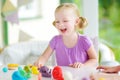 Cute little girl having fun with modeling clay at a daycare. Creative kid molding at home. Royalty Free Stock Photo