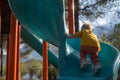 Cute little girl having fun on outdoor playground. Child on plastic slide. Royalty Free Stock Photo