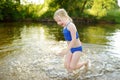 Cute little girl having fun on a sandy lake beach on warm and sunny summer day. Kid playing by the river Royalty Free Stock Photo