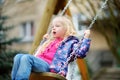 Cute little girl having fun on a swing on beautiful spring day.