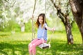 Cute little girl having fun on a swing in blossoming old apple tree garden outdoors on sunny spring day. Royalty Free Stock Photo