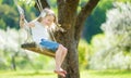 Cute little girl having fun on a swing in blossoming old apple tree garden outdoors on sunny spring day Royalty Free Stock Photo