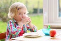 Cute little girl having toast and milk for breakfast