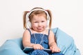 Cute little girl in headphones listening to music using a tablet and smiling while sitting on blue big bag Royalty Free Stock Photo