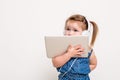 Cute little girl in headphones listening to music using a tablet and smiling on white background Royalty Free Stock Photo