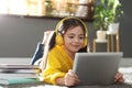 Cute little girl with headphones and tablet listening to audiobook