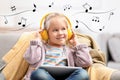 Cute girl with headphones and tablet listening to music at home