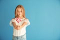 Cute little girl with heart-shaped lollipop on color background Royalty Free Stock Photo