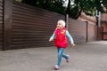 Cute little girl heerfully spending time while running at city street on the summer day Royalty Free Stock Photo