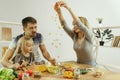 Cute little girl and her beautiful parents are cutting vegetables in kitchen at home Royalty Free Stock Photo