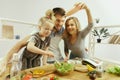 Cute little girl and her beautiful parents are cutting vegetables in kitchen at home Royalty Free Stock Photo