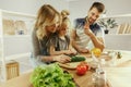 Cute little girl and her beautiful parents are cutting vegetables in kitchen at home Royalty Free Stock Photo