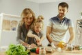 Cute little girl and her beautiful parents are cutting vegetables in kitchen at home Royalty Free Stock Photo