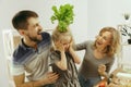 Cute little girl and her beautiful parents are cutting vegetables in kitchen at home Royalty Free Stock Photo