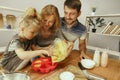 Cute little girl and her beautiful parents preparing the dough for the cake in kitchen at home Royalty Free Stock Photo