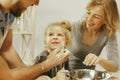 Cute little girl and her beautiful parents preparing the dough for the cake in kitchen at home Royalty Free Stock Photo