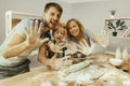 Cute little girl and her beautiful parents preparing the dough for the cake in kitchen at home Royalty Free Stock Photo
