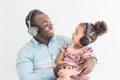 Cute little girl and her dad are listening to music with headphones on a white background Royalty Free Stock Photo