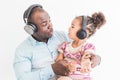 Cute little girl and her dad are listening to music with headphones on a white background Royalty Free Stock Photo