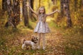 Cute little girl with her dog in autumn park. Lovely child with dog walking in fallen leaves. Royalty Free Stock Photo