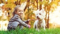 Cute little girl with her dog in autumn park. Lovely child with dog walking in fallen leaves. Stylish little girl enjoying colourf