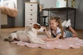 Cute little girl with her dog on floor at home. Childhood pet Royalty Free Stock Photo