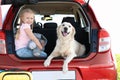 Cute little girl  her dog in open car trunk Royalty Free Stock Photo