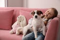 Cute little girl with her dog on sofa, space for text. Childhood pet Royalty Free Stock Photo