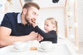 Cute little girl and her father drink tea with cookies at home.