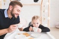 Cute little girl and her father drink tea with cookies at home.