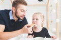 Cute little girl and her father drink tea with cookies at home.