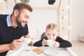 Cute little girl and her father drink tea with cookies at home.