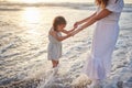Cute little girl and her mixed race mother playing in the water at the beach. Young daughter and her mom spending Royalty Free Stock Photo