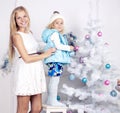 Cute little girl with her mom decorating Christmas tree