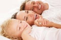 Cute little girl with her parents lying on bed