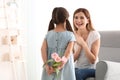 Cute little girl hiding flowers for mother behind her back