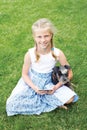 Little girl with his dog sitting on green grass and read e-book. Royalty Free Stock Photo