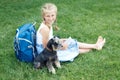 Little girl with his dog sitting on green grass and read e-book. Royalty Free Stock Photo