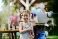 Little girl hodling fresh lemonades in glass bottle. Summer garden party at backyard.