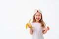 Cute little girl holding a banana in her hand, looks very happy, isolated