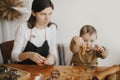 Cute little girl holding christmas cookie on table, close up. Adorable toddler daughter helps mother making gingerbread cookies. Royalty Free Stock Photo