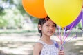 Cute little girl holding colorful balloons in the meadow against blue sky and clouds,spreading hands Royalty Free Stock Photo