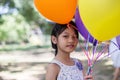 Cute little girl holding colorful balloons in the meadow against blue sky and clouds,spreading hands Royalty Free Stock Photo