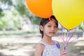 Cute little girl holding colorful balloons in the meadow against blue sky and clouds,spreading hands Royalty Free Stock Photo