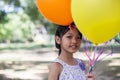 Cute little girl holding colorful balloons in the meadow against blue sky and clouds,spreading hands Royalty Free Stock Photo