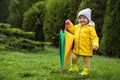 Cute little girl holding colorful umbrella and standing in garden, space for text Royalty Free Stock Photo