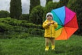 Cute little girl holding colorful umbrella and standing in garden, space for text Royalty Free Stock Photo