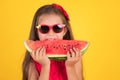 Cute little girl holding, eating  juicy slice of watermelon over yellow background Royalty Free Stock Photo